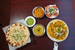 Assortment of Sheesh Mahal food includes, from left, garlic naan, daal, butter chicken, malai tikka chicken and a plate of rice biryani. (Mark Hancock)