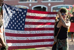 Marchers display a flag with the names of blacks killed by police during a Black Lives Matter rally and march July 10 in Bricktown. (Emmy Verdin)