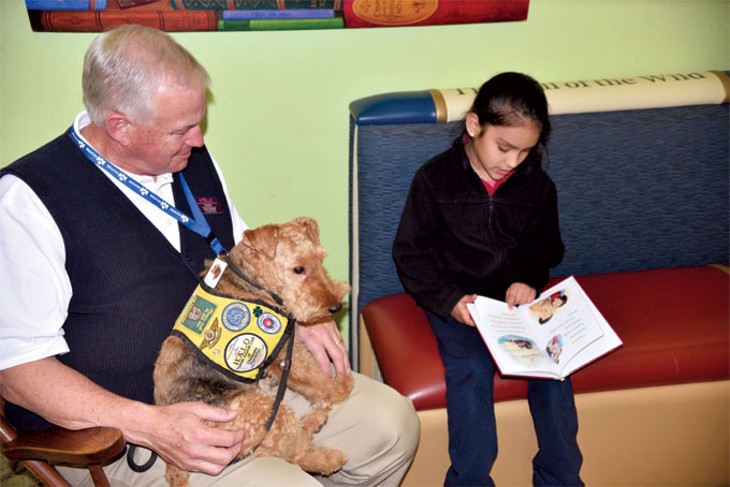Brianna Montalvo reads to Charley the dog and her owner Jerry Nickell at The Village Library. | Photo Jacob Threadgill
